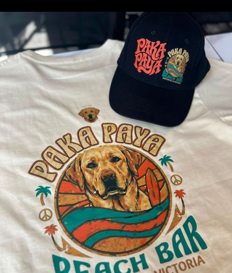 Camiseta crema y gorra negra PakáPayá Beach Bar con el logo del perro