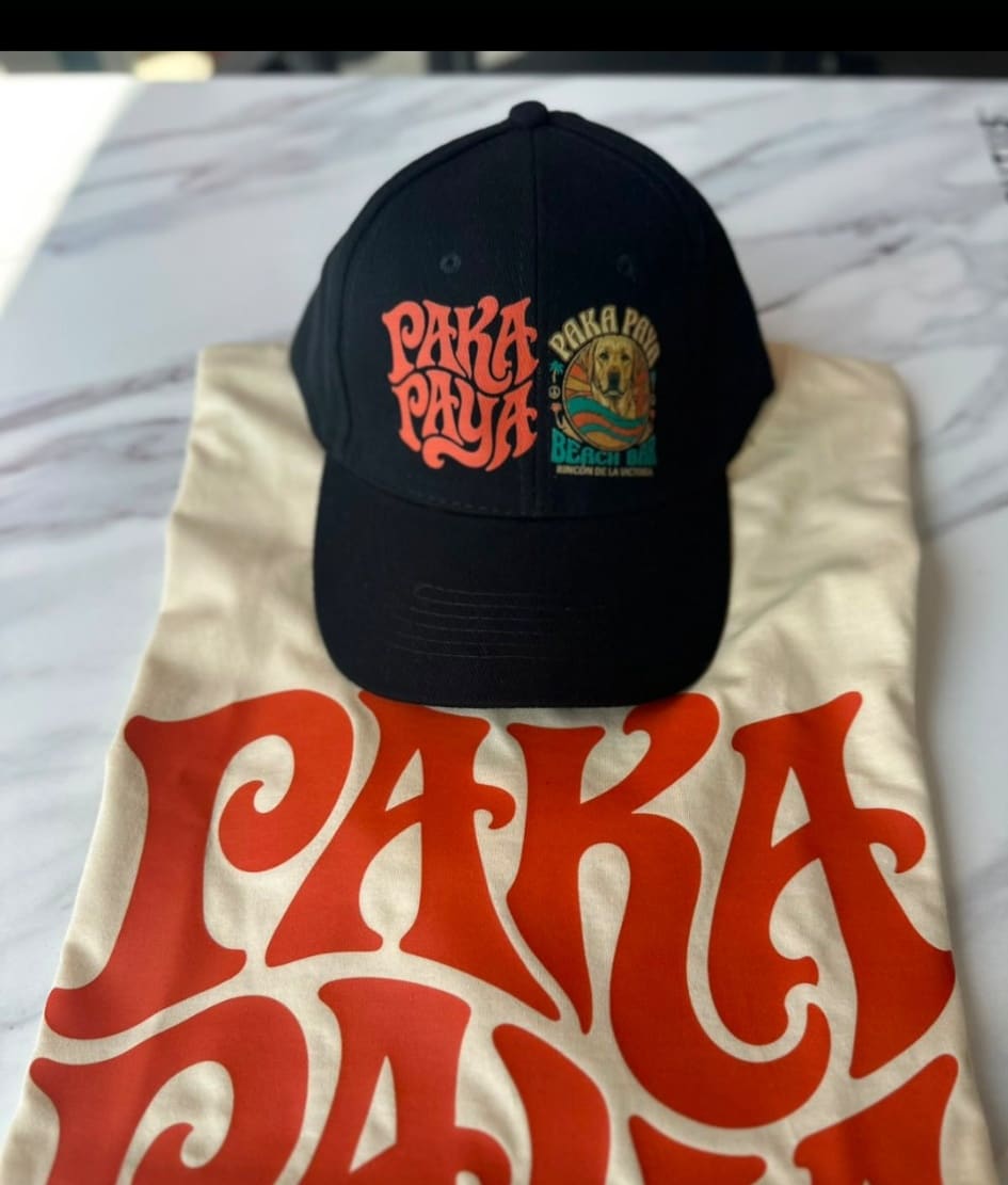 Gorra negra PakáPayá sobre camiseta crema con el logo delante