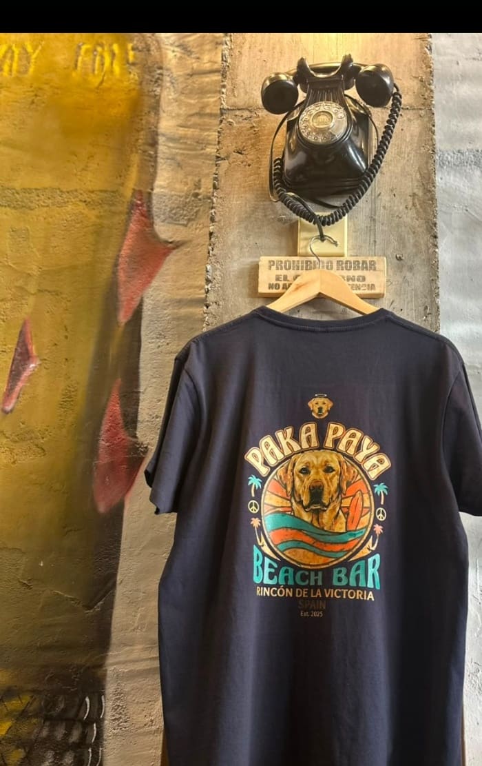 Camiseta azul marino PakáPayá colgada junto al teléfono vintage del local